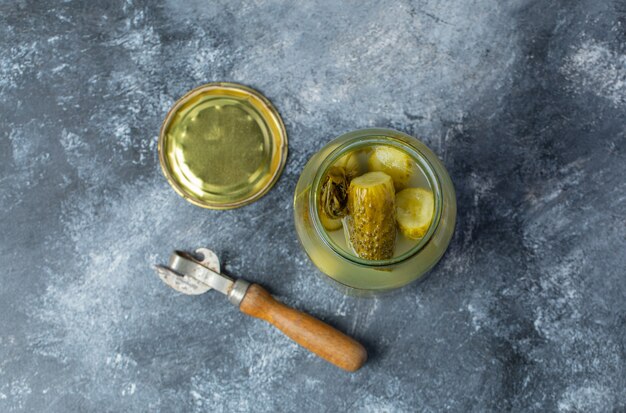 Top view of Opened jar full with pickled cucumber on grey background