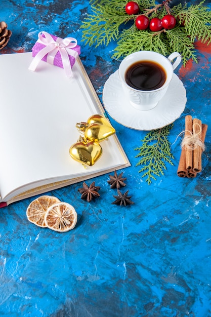 Top view opened notebook fir tree branches cones xmas tree toys on blue surface