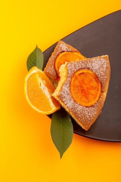 A top view orange cake slice sweet delicious tasty piece on the brown colored wooden desk and yellow background sweet sugar biscuit