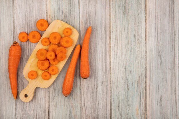 Top view of orange chopped carrots on a wooden kitchen board with carrots isolated on a grey wooden surface with copy space