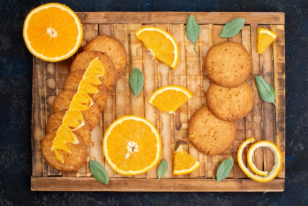 Foto gratuita una vista dall'alto biscotti aromatizzati all'arancia con fette d'arancia fresche sullo sfondo scuro zucchero frutta biscotto