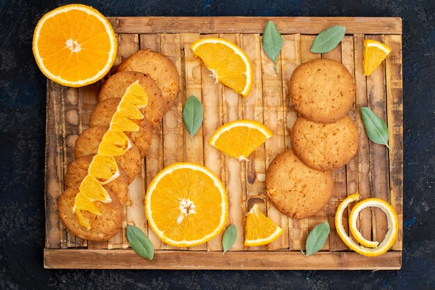 A top view orange flavored cookies with fresh orange slices on the dark background cookie sugar  fruit