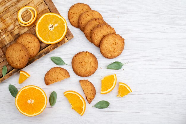 Вид сверху печенье со вкусом апельсина со свежими дольками апельсина на светлом столе, печенье с фруктами