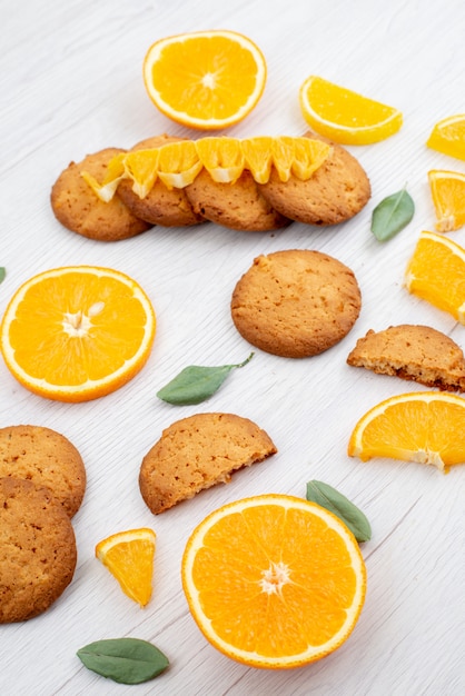 A top view orange flavored cookies with fresh orange slices on the light desk fruit cookie