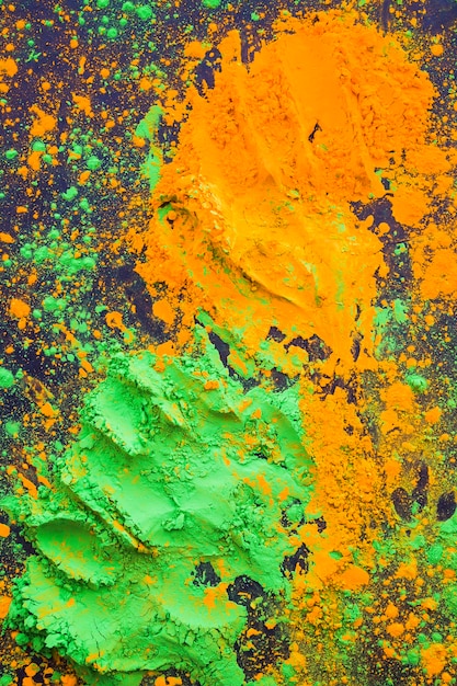 Top view of orange and green splatter of holi powder backdrop