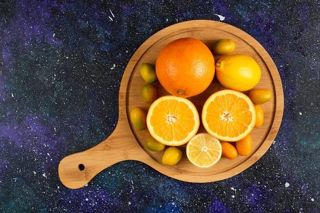 Top view of orange and lemon, half cut or whole over wooden board.