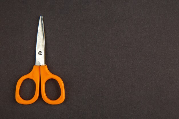 top view orange scissors on dark background