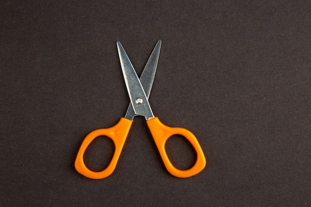 top view orange scissors on dark background