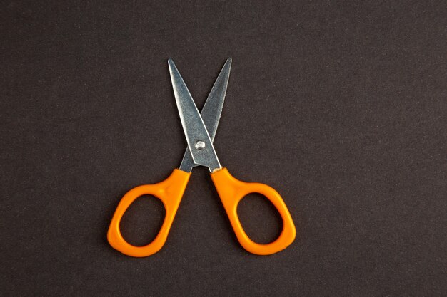 top view orange scissors on dark background
