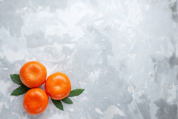 Vista dall'alto mandarini arancioni interi agrumi sulla scrivania bianca agrumi succo di frutta esotica