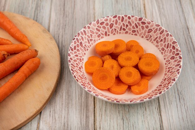 회색 나무 벽에 그릇에 오렌지 맛있는 다진 당근의 상위 뷰