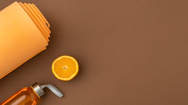 Top view orange yoga mat and water bottle