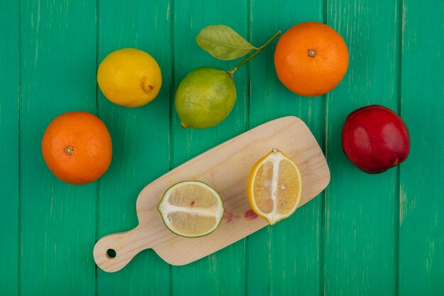 Top view oranges with lime and lemon on a cutting board  on a green background