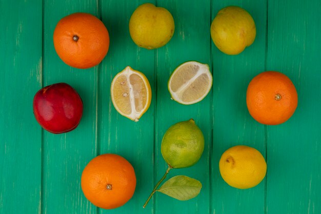 Top view oranges with lime and lemon on green background