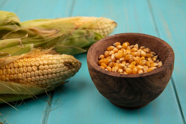 Free photo top view of organic corns with hair with corn kernels on a wooden bowl on a blue wooden table