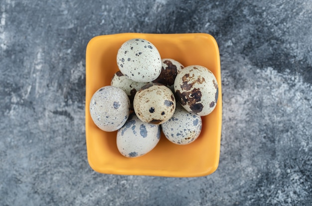 Top view of organic farm quail egg in yellow bowl.