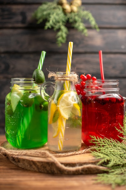 Top view of organic fuit juices in bottles served with tubes on a wooden cutting board