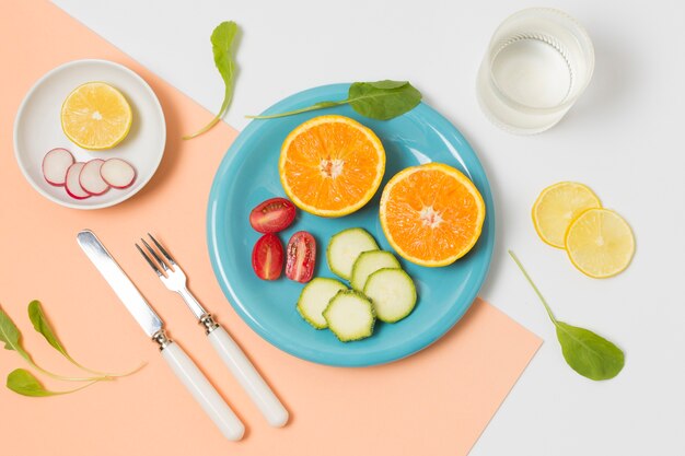 Вид сверху органических апельсинов и овощей на тарелке