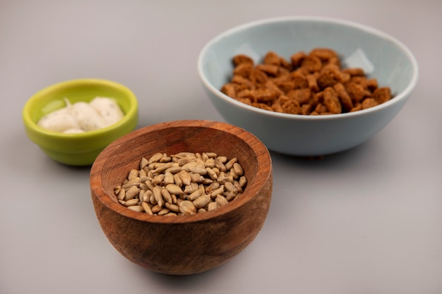 Top view of organic shelled sunflower seeds on a wooden bowl with tasty rye rusks with sauce