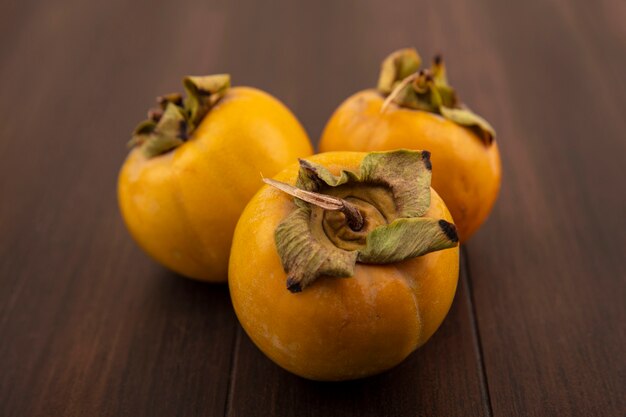 Top view of organic unripe persimmon fruits isolated on a wooden table