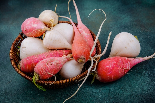 Free photo top view of organic white and pinkish red root vegetable beetroots on a bucket on a green background