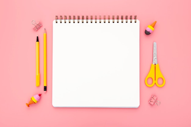 Top view organised arrangement of desk elements on pink background