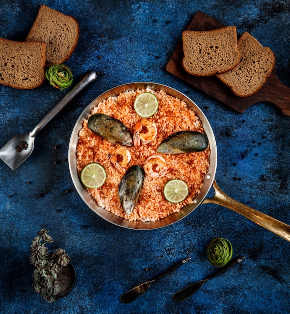 Free photo top view of paella with mussels and shrimp in a pan on blue