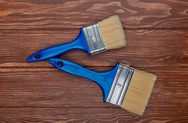 Top view of paint brushes on wooden background