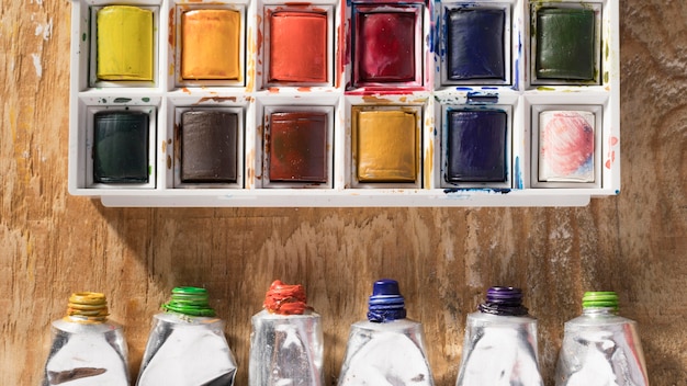 top view of paint tubes and palette on wooden surface