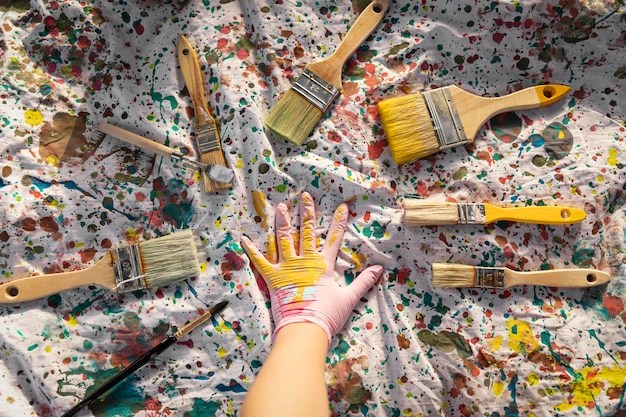 Top view of paintbrushes with paint and artist hand