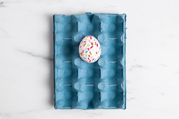 Top view of painted easter egg in carton