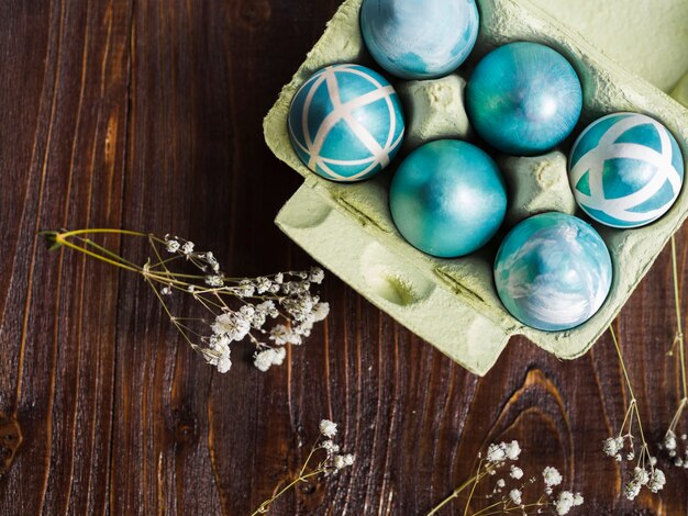 Top view of painted easter eggs in carton  with gypsophila