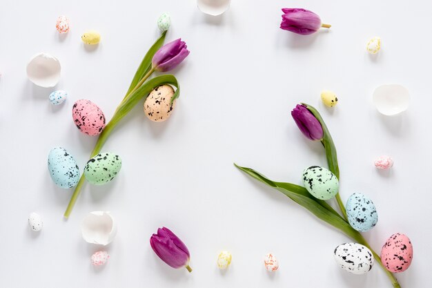 Top view painted eggs and flowers on table