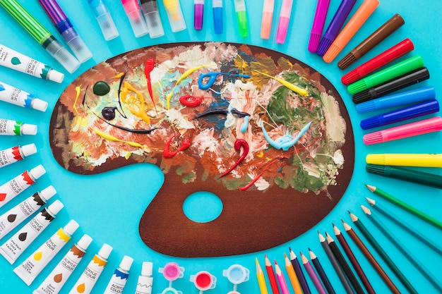 Top view painting palette surrounded by painting elements