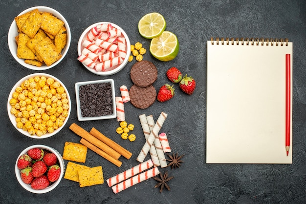 Free photo top view panatable snack receipe with fresh lemon and stawberries near to blank notebook pen on the black surface with free space