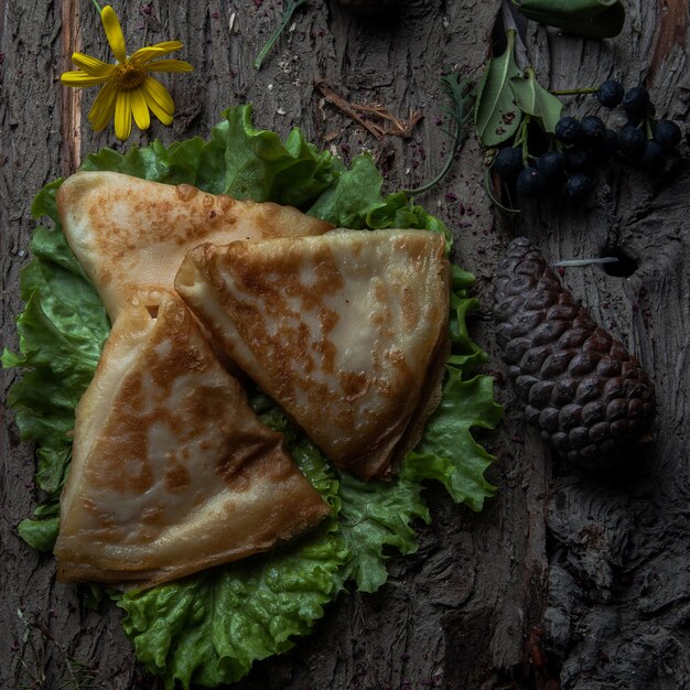 Top view pancakes with cheese on a salad on a wooden bark