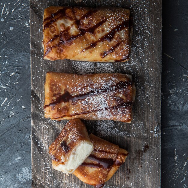 Frittelle vista dall'alto con sciroppo di cioccolato e ricotta e zucchero a velo nel tagliere