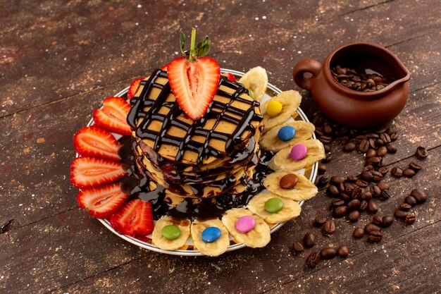 top view pancakes with fresh fruits and chocolate on the brown wooden floor