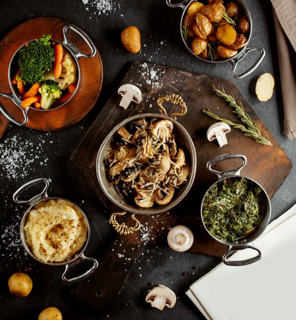 Top view of pans with mushroom sautee mashed potato sabzi boiled vegetables and roasted potatoes