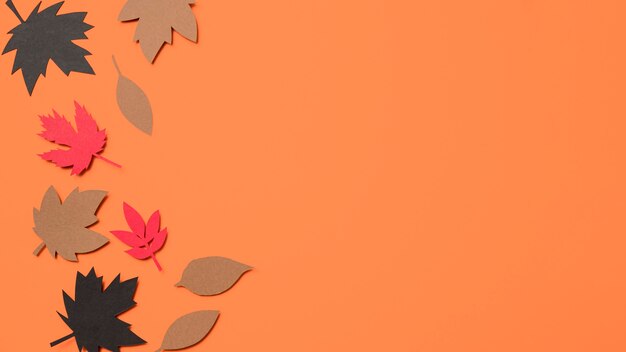 Top view paper autumn leaves on orange background with copy space