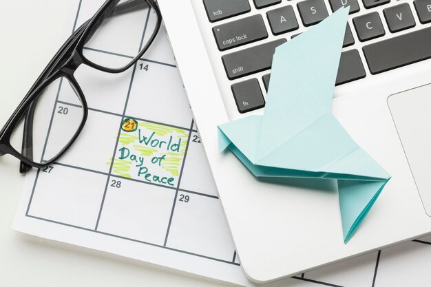 Вид сверху бумаги голубя с ноутбуком и Всемирным днем мира