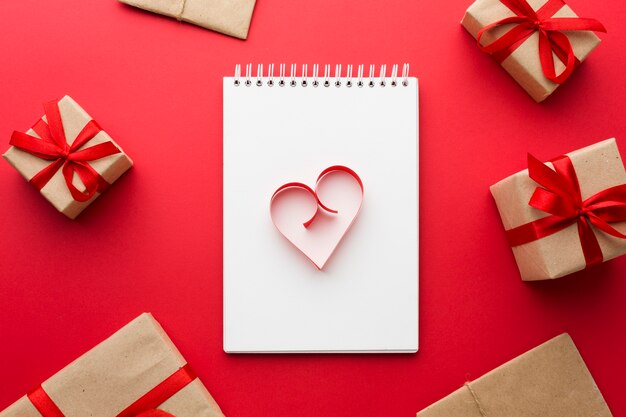 Вид сверху бумаги в форме сердца на блокнот с подарками