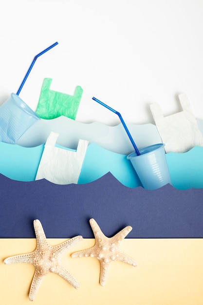 Top view of paper ocean waves with plastic cup and starfish