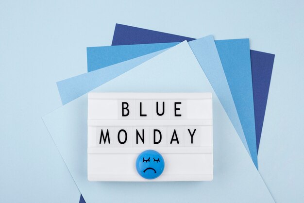 Top view of paper with sad face and light box for blue monday