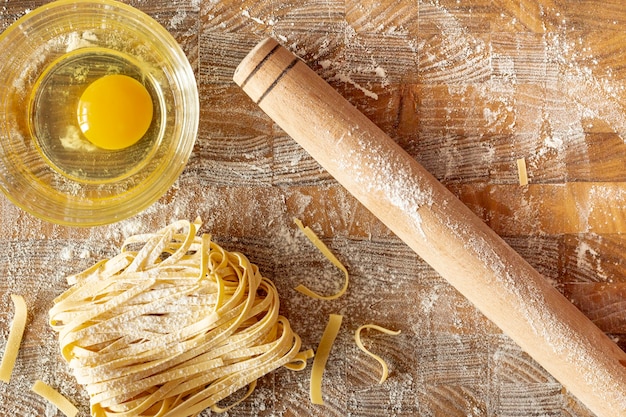 Top view of pasta and egg on wooden background