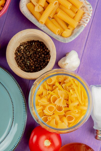 Top view of pasta in jar with black pepper and tomatoes