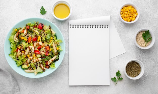 Top view pasta salad with balsamic vinegar and blank notepad