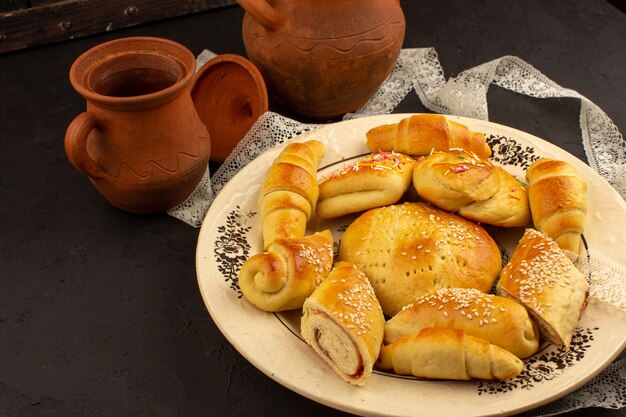 top view pastries along with croissants inside glass plate on the dark background