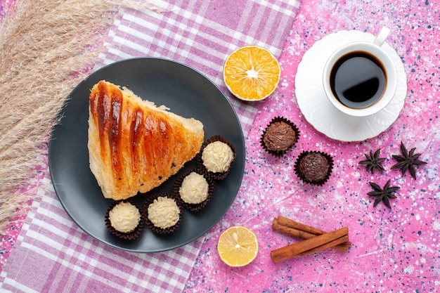 Top view of pastry slice with cinnamon and chocolate candies on pink surface