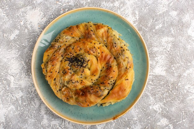 Top view of pastry with meat delicious dough meal inside plate on light surface